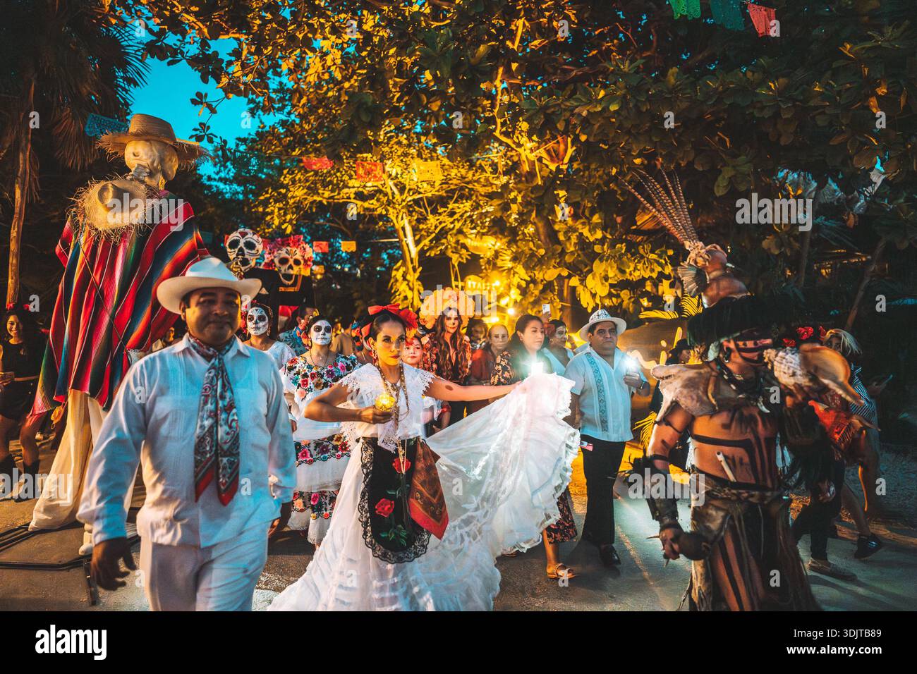 Vibrant Day of the Dead procession in Tulum, Mexico, featuring dancers, traditional costumes, painted faces, and oversized skeleton figures illuminate Stock Photo