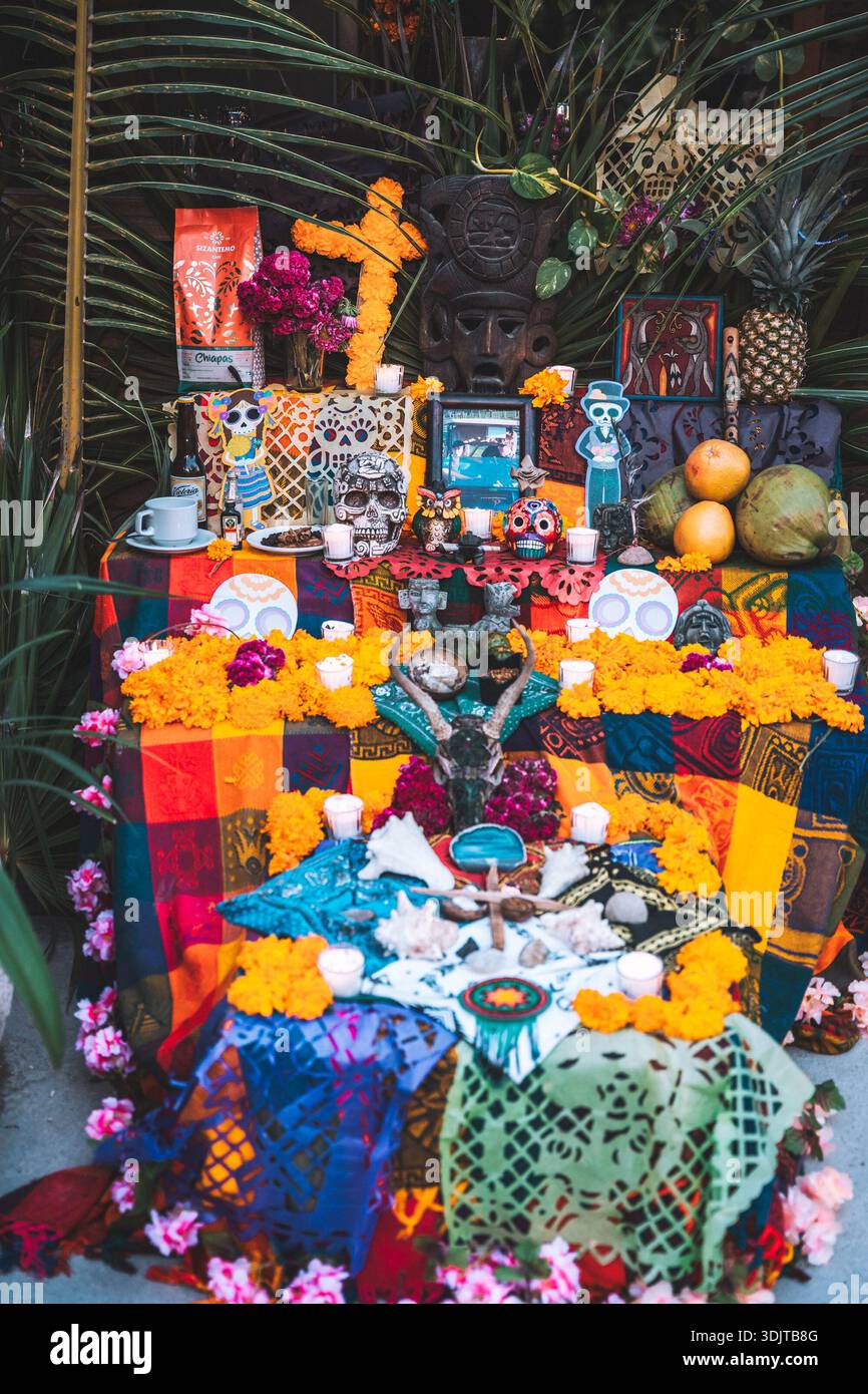 Traditional multi-tier Day of the Dead altar featuring marigolds, candles, sugar skulls, food offerings, and papel picado in Tulum, Mexico. Stock Photo