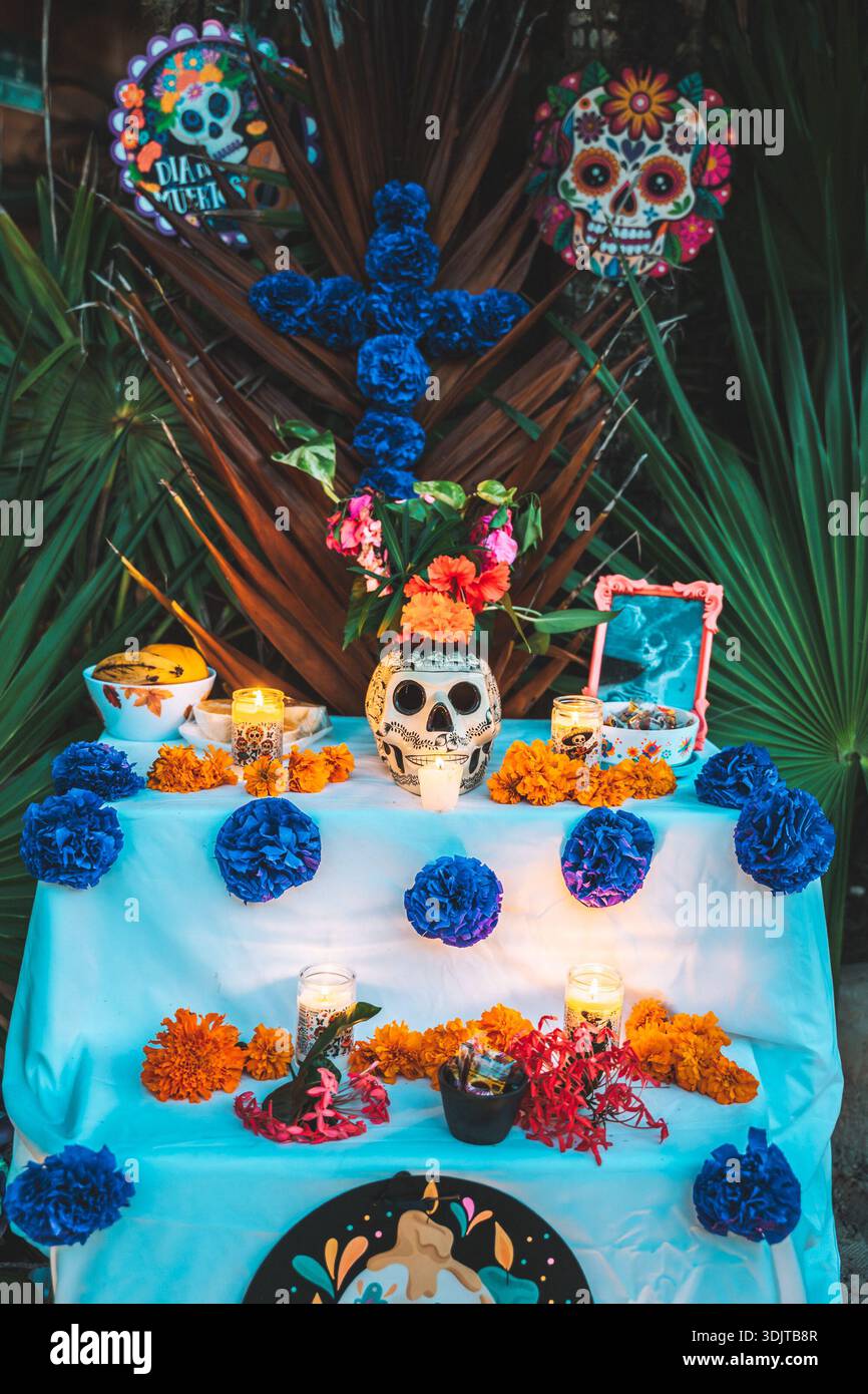 Blue-themed Day of the Dead altar decorated with marigolds, candles, skull imagery, and papel picado in Tulum, Mexico. Stock Photo
