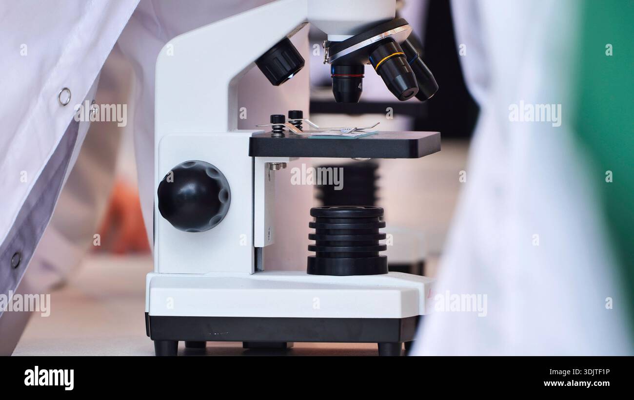Scientists performing close-up work with microscopes in a modern science laboratory setting Stock Photo