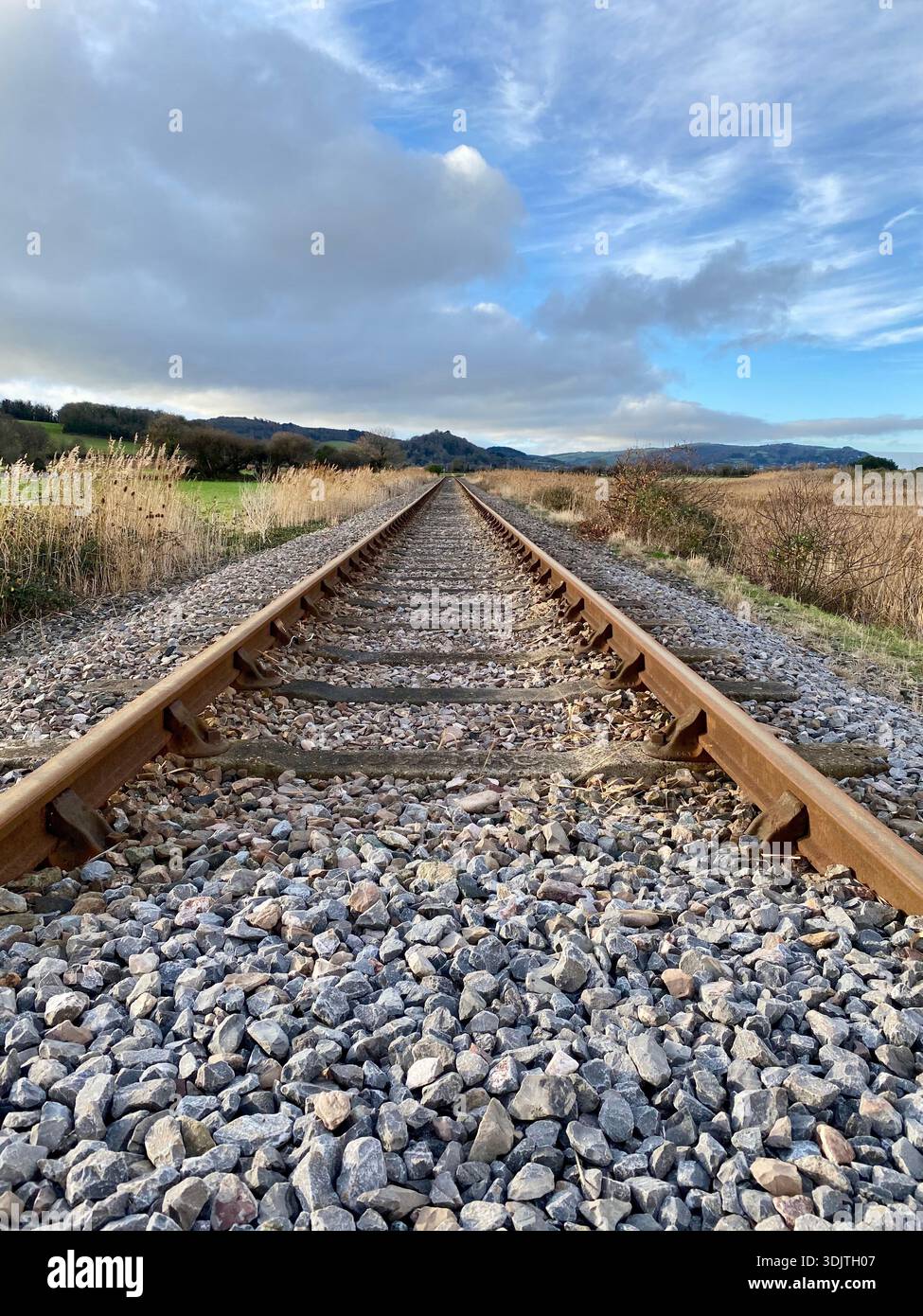 Railway track disappearing into rural countryside with dramatic sky - Smartphone Captured Stock Image