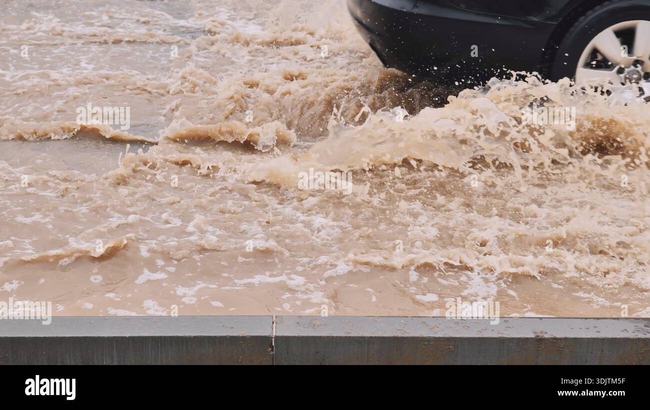 Car driving through flooded urban street splashing muddy water during ...