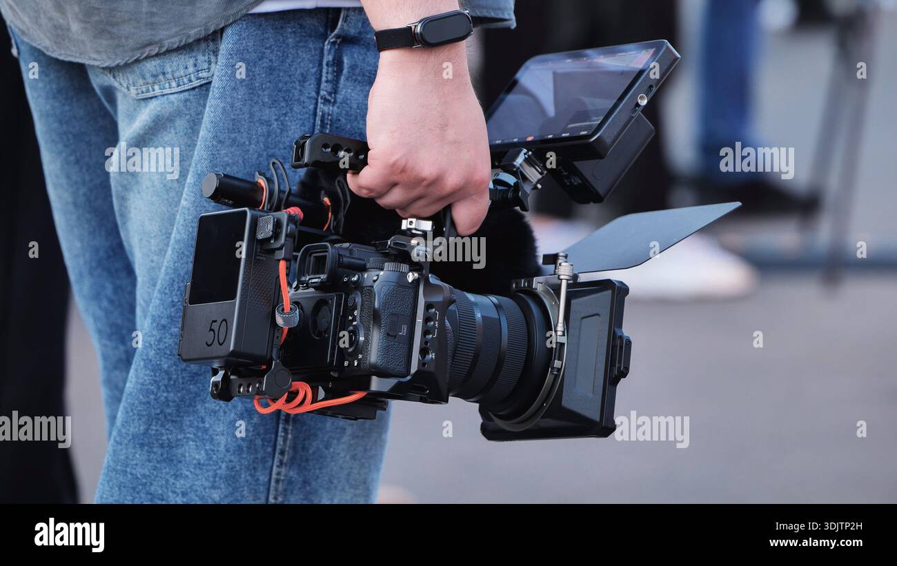 Filmmaker holding professional cinema camera rig with monitor and matte box Stock Photo