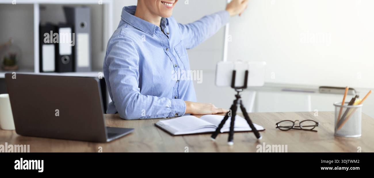 Person Presenting a Virtual Lesson While Using a Laptop and Tablet in a Modern Workspace Stock Photo