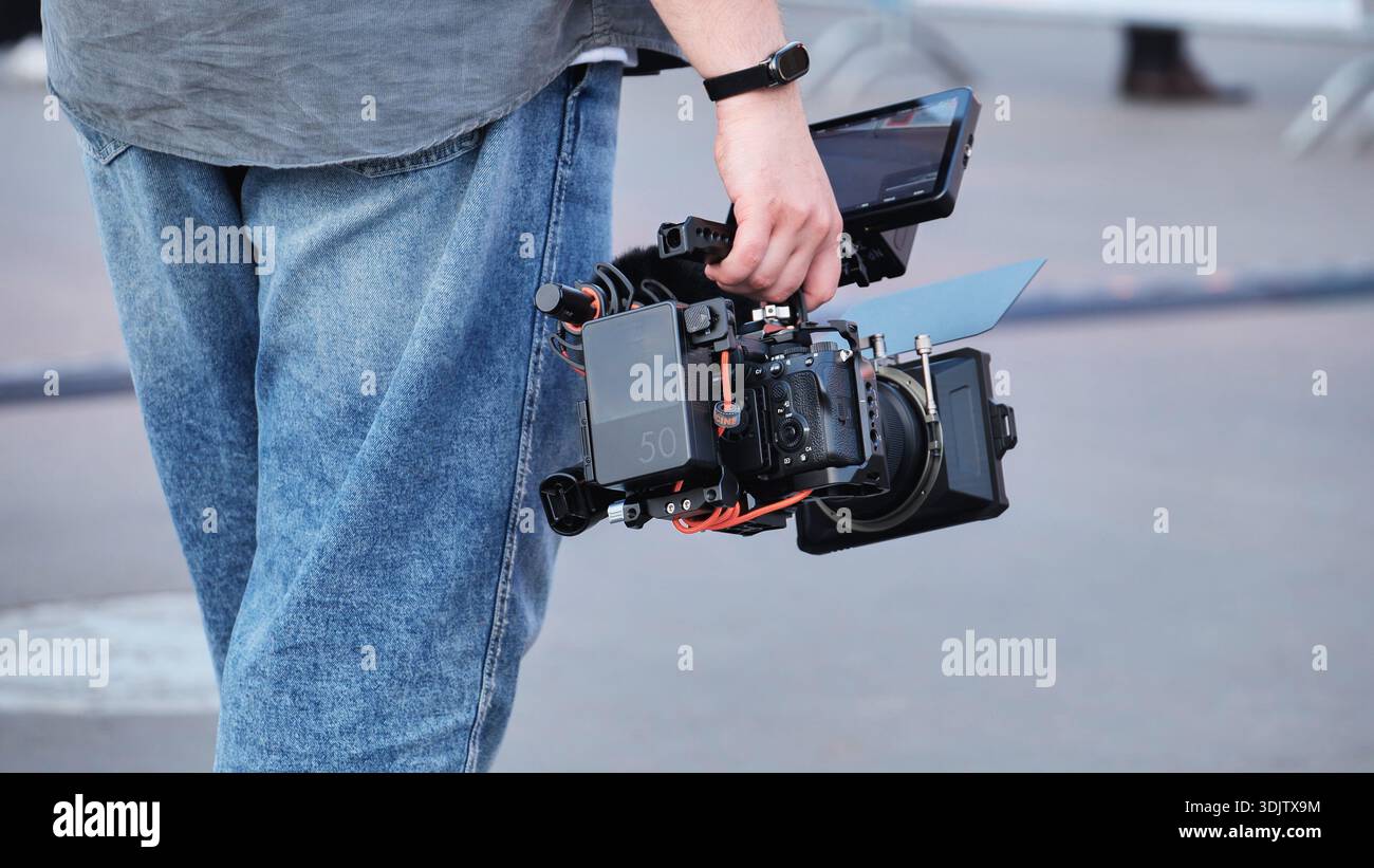 Videographer carrying professional cinema camera rig filming for media production Stock Photo