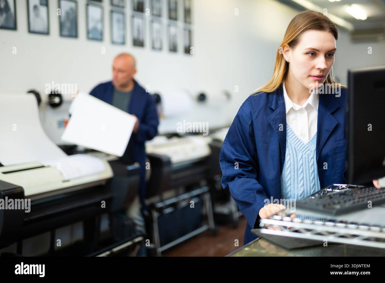 Technician operator calibrating plotter machine, typing on computer keyboard Stock Photo