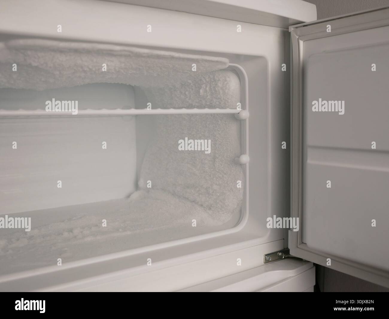 Empty freezer with heavy frost and ice buildup. Cold storage concept, refrigeration problem, defrost need, appliance maintenance, food safety, copy sp Stock Photo