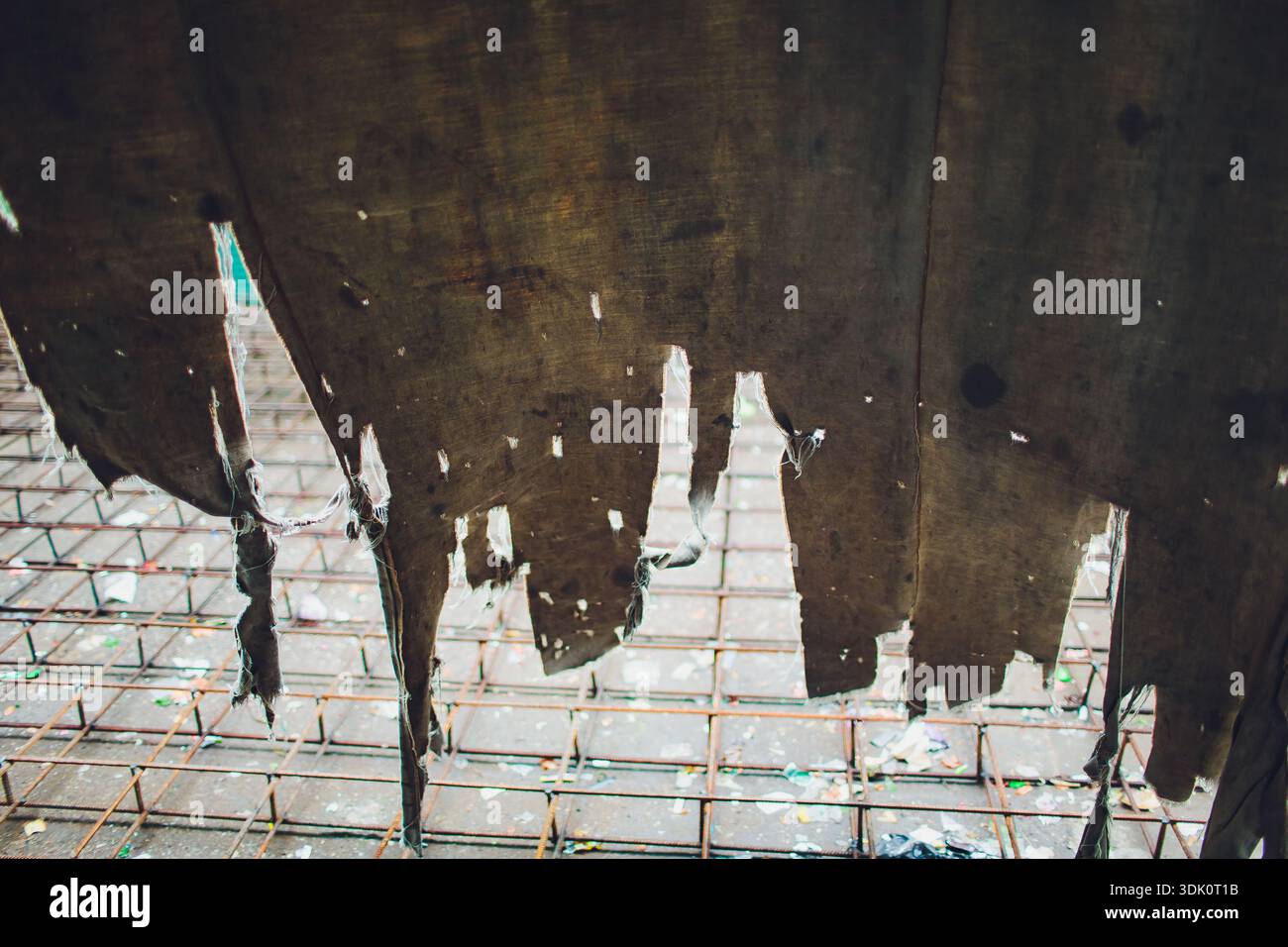 Abandoned decay visible. Rusty iron bars and worn canvas. Dusty concrete with peeling fabric fragments. Old structure showing corrosion and weathered Stock Photo