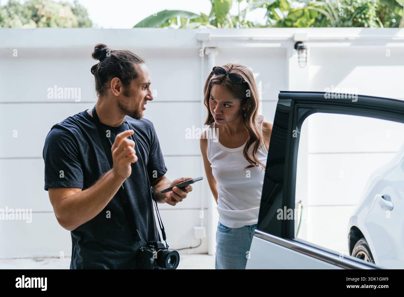 Couple having serious discussion standing next to car Stock Photo
