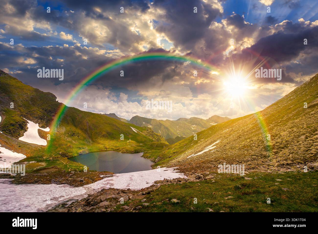 mountain lake in alpine summer landscape at sunset. beautiful view surrounded with clouds on a blue sky in evening light. fresh water, snow and rocky Stock Photo
