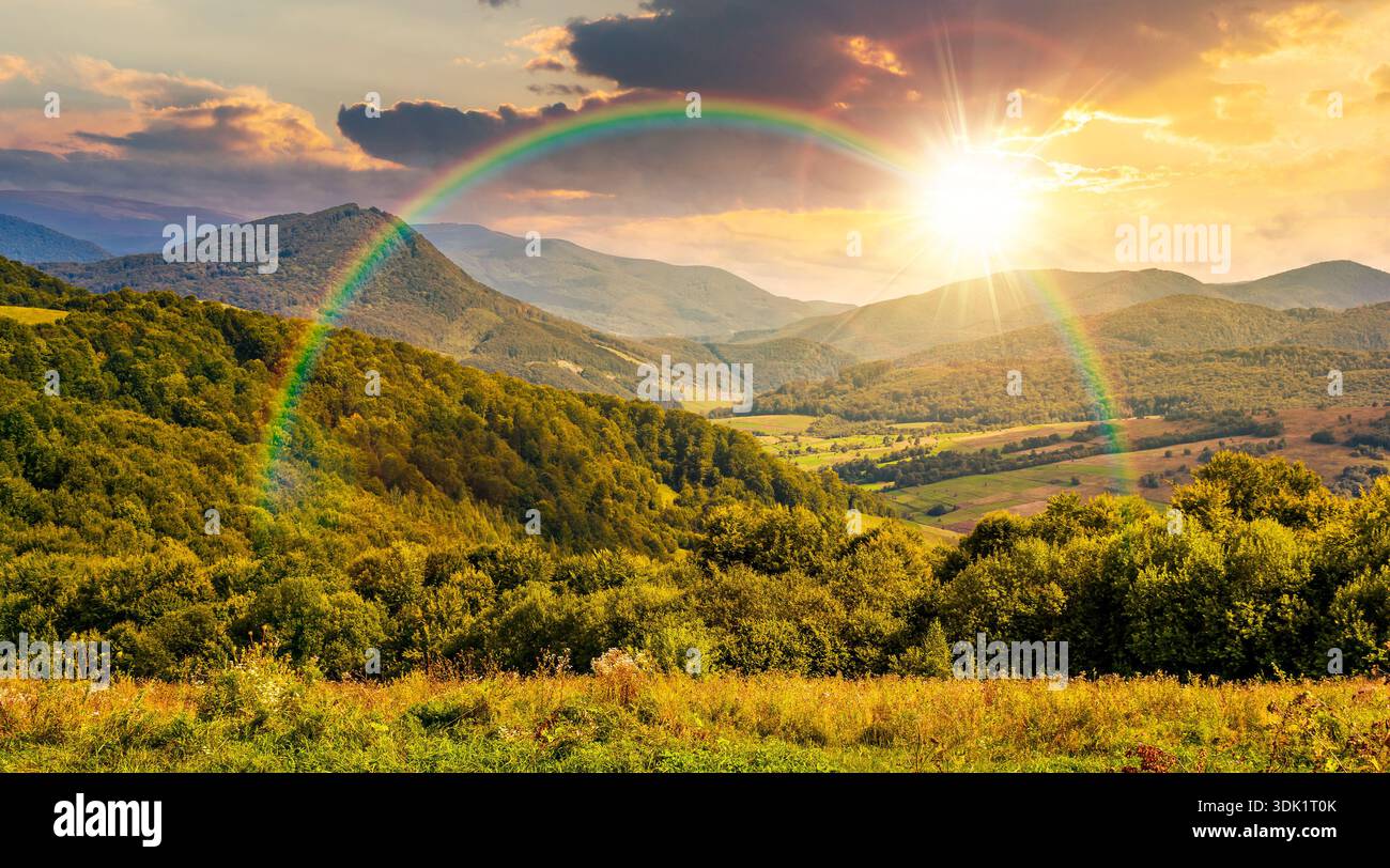 mountainous countryside scenery surrounded with forested rolling hills at sunset. rural area peaceful landscape with cloudy sky in evening light. earl Stock Photo