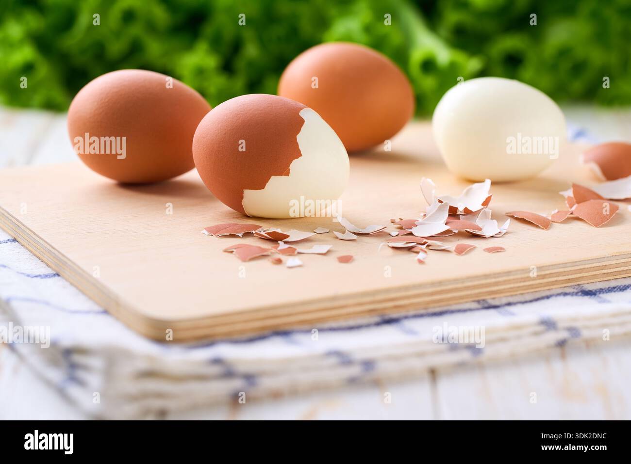 Fresh hard boiled eggs with shell beside in a cutting board, selective focus. Stock Photo