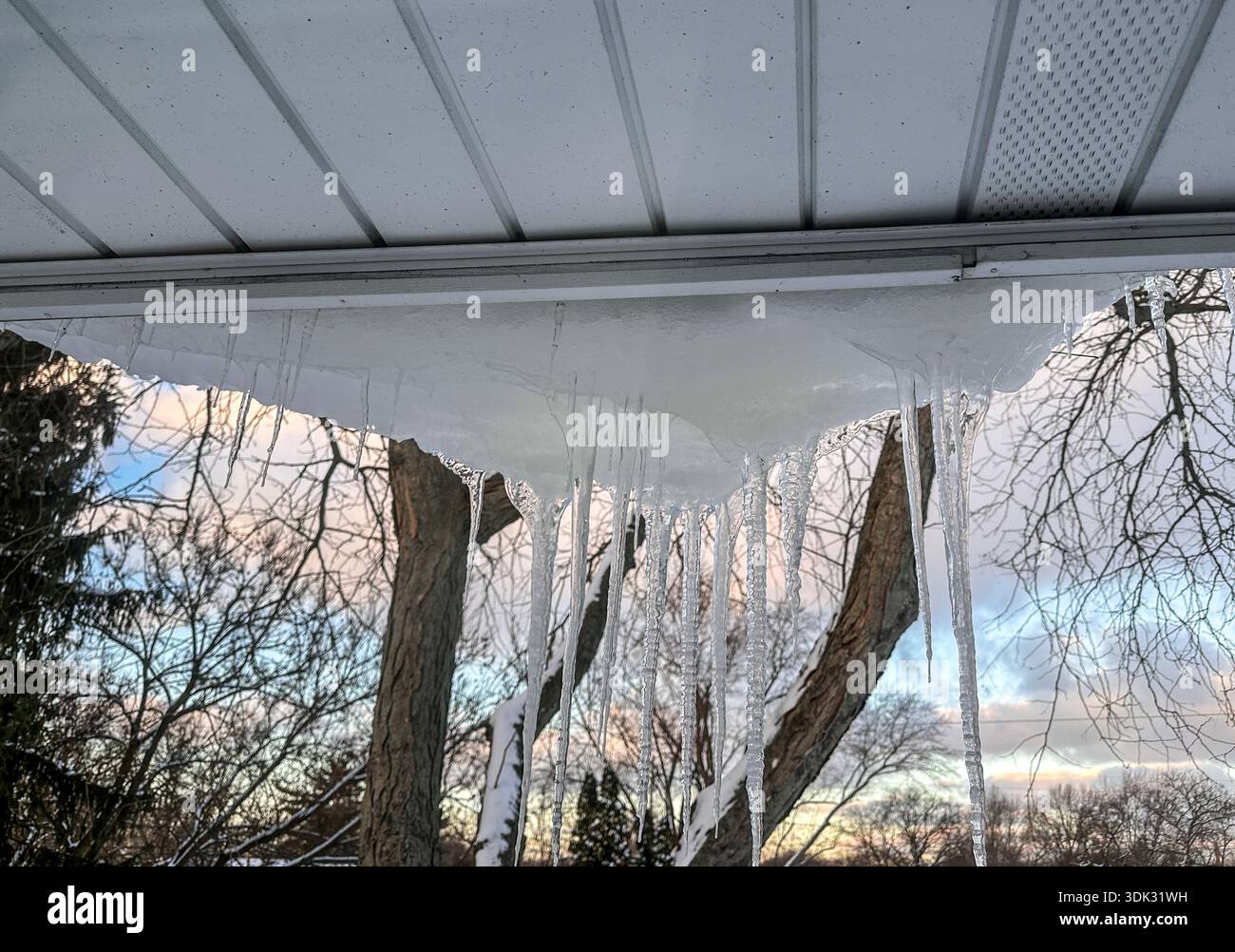 Large icicles hanging from a roof in winter Stock Photo