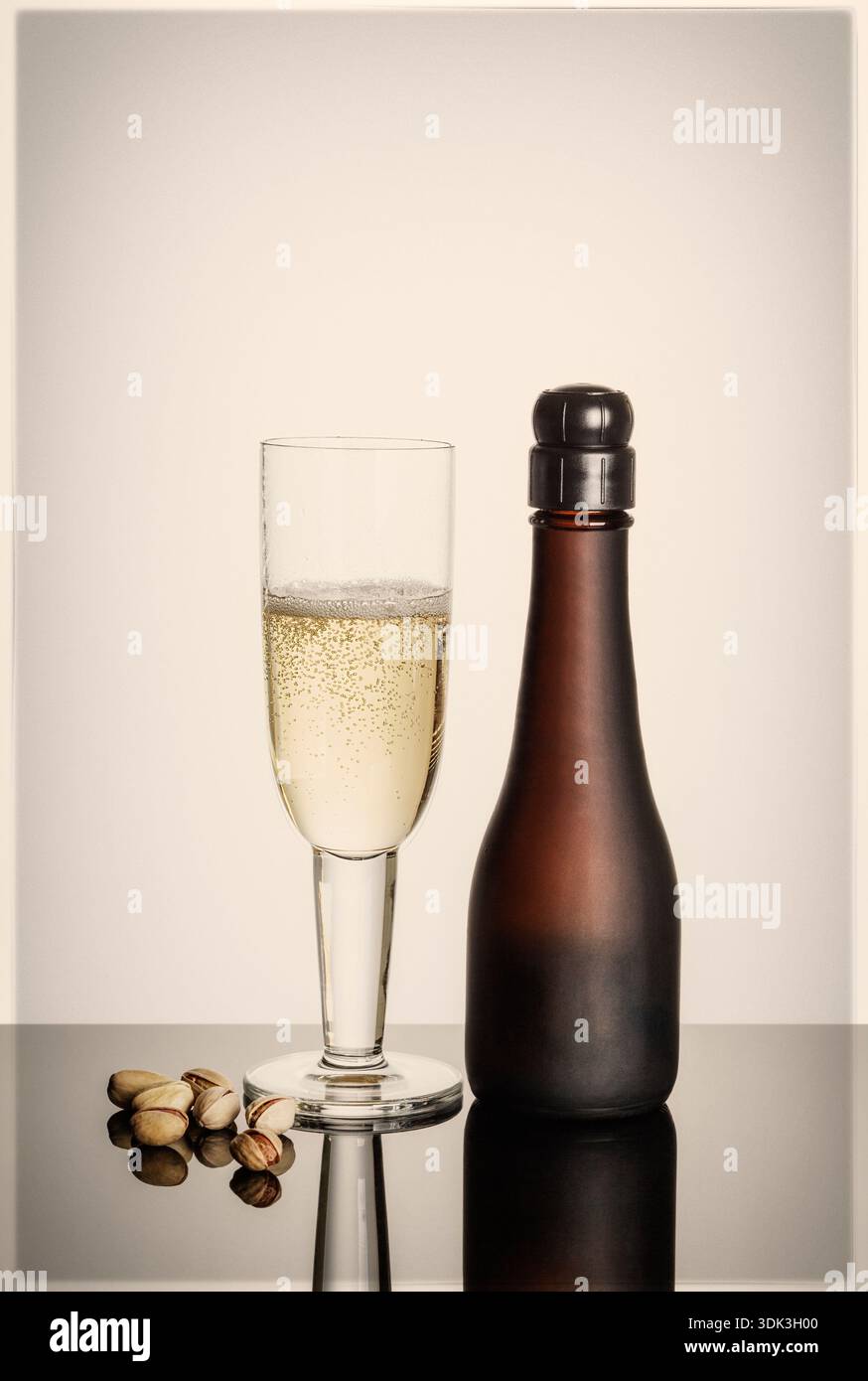 Small champagne bottle with champagne flute and pistachio nuts Stock Photo