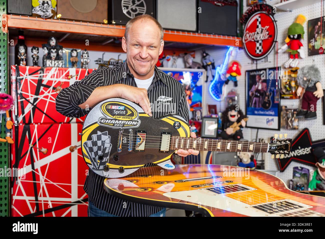 NASCAR artist Sam Bass stands proudly beside his vibrant artwork at his ...