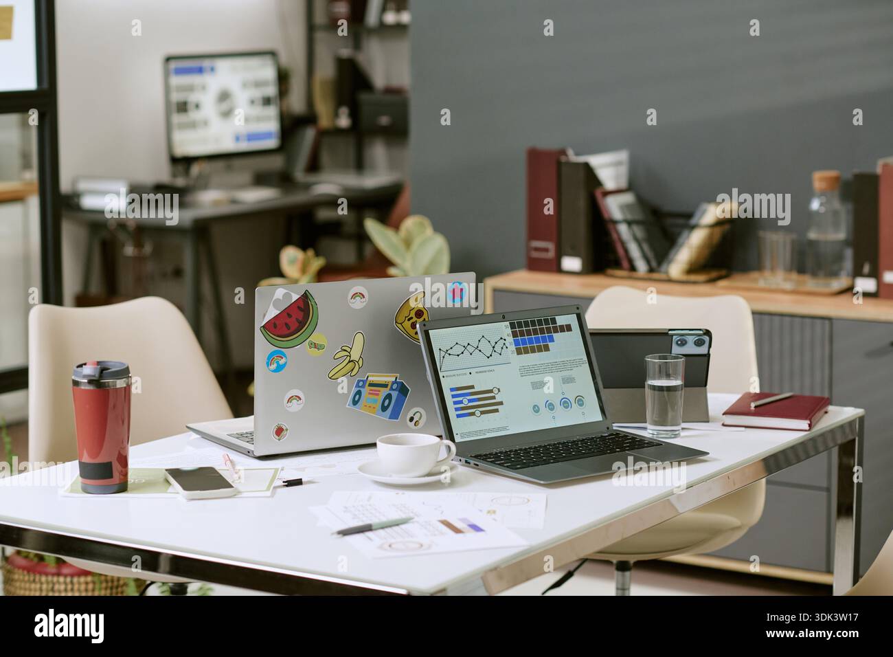Modern Office Workspace Featuring Laptops Displaying Data Analytics Graphs Stock Photo