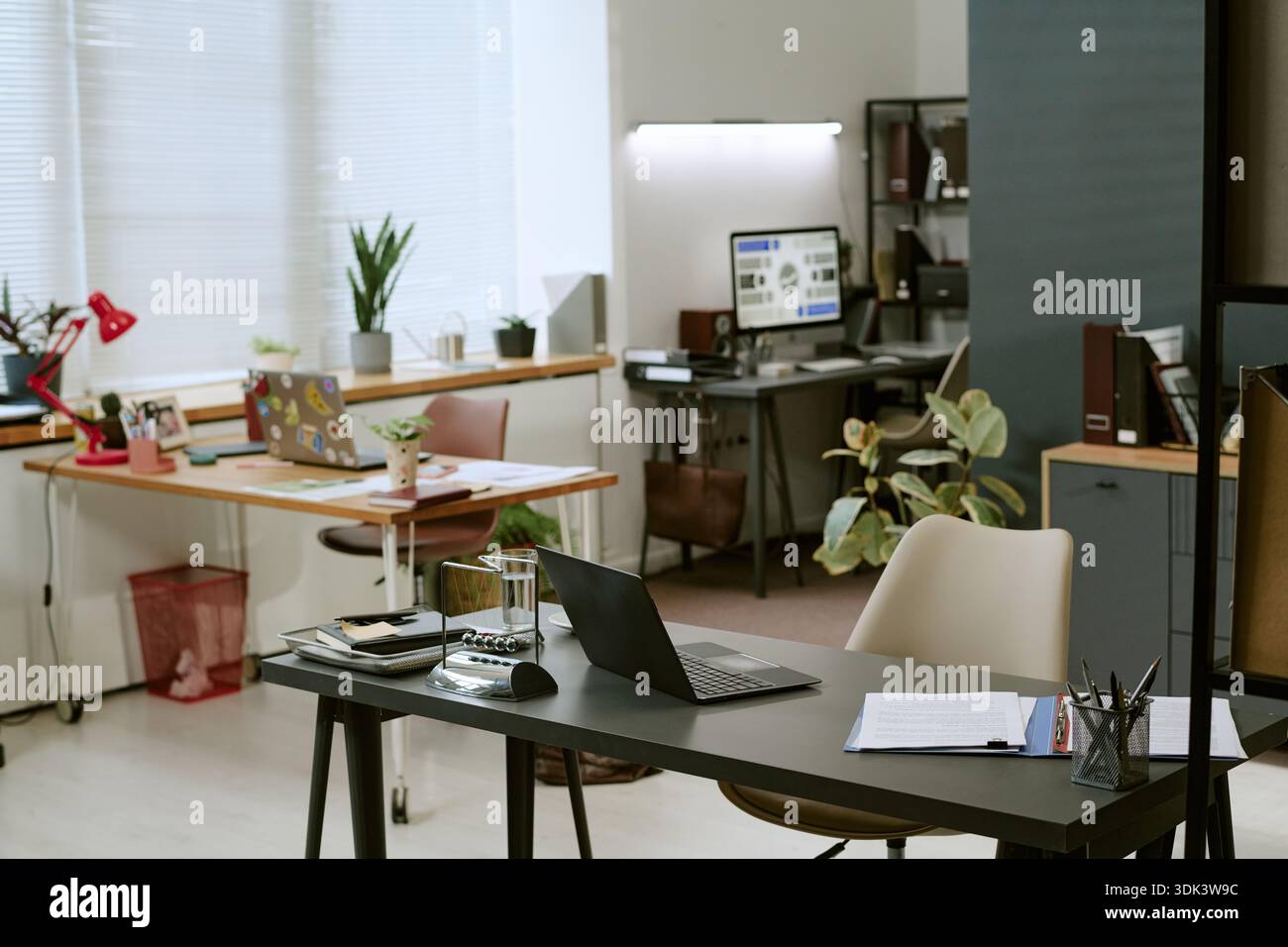 Modern Office Interior Featuring Laptops and Documents on Desks Stock Photo
