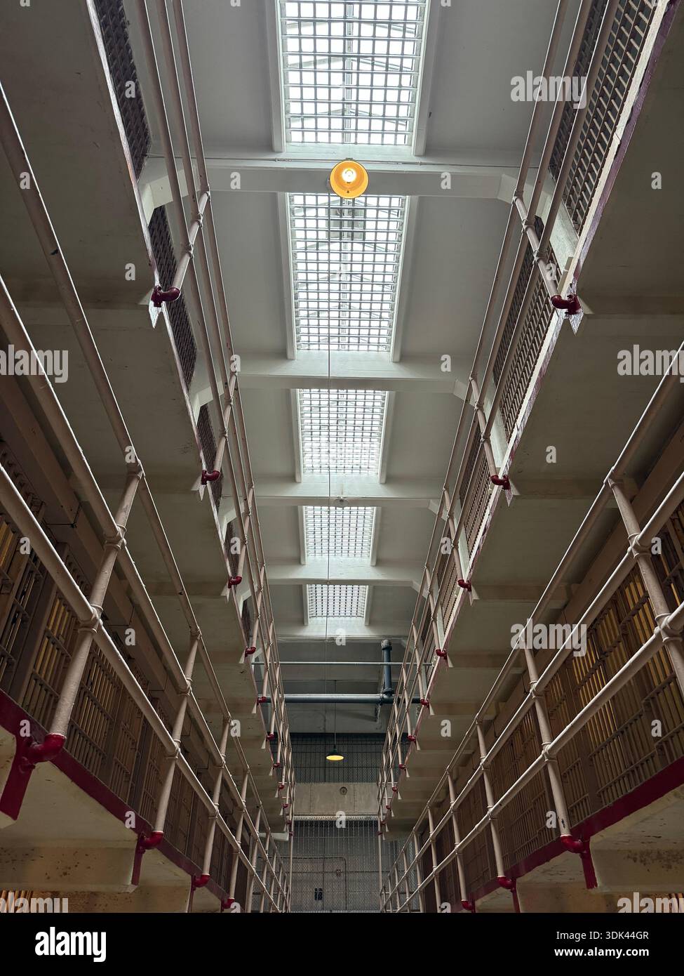 Symmetrical interior view of an abandoned prison cell block corridor with skylights and metal bars, industrial architecture perspective. - Smartphone Captured Stock Image