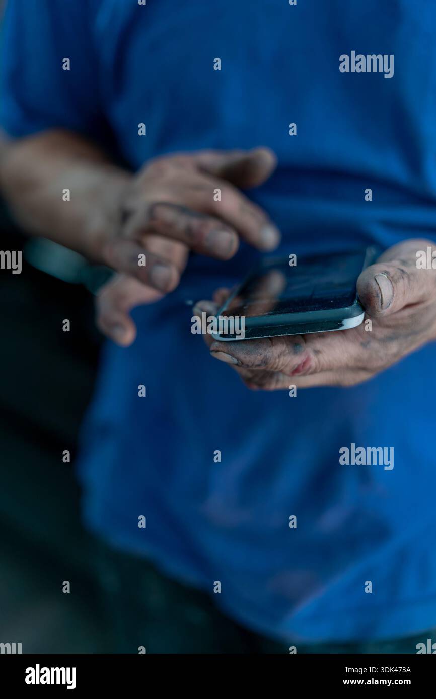 mechanic's hands using a cell phone Stock Photo