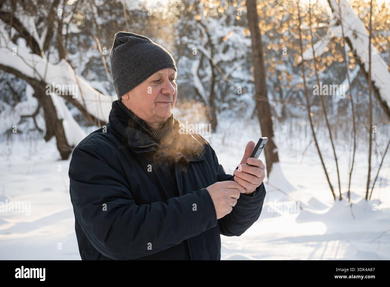 Senior man using smartphone outdoors in winter Stock Photo