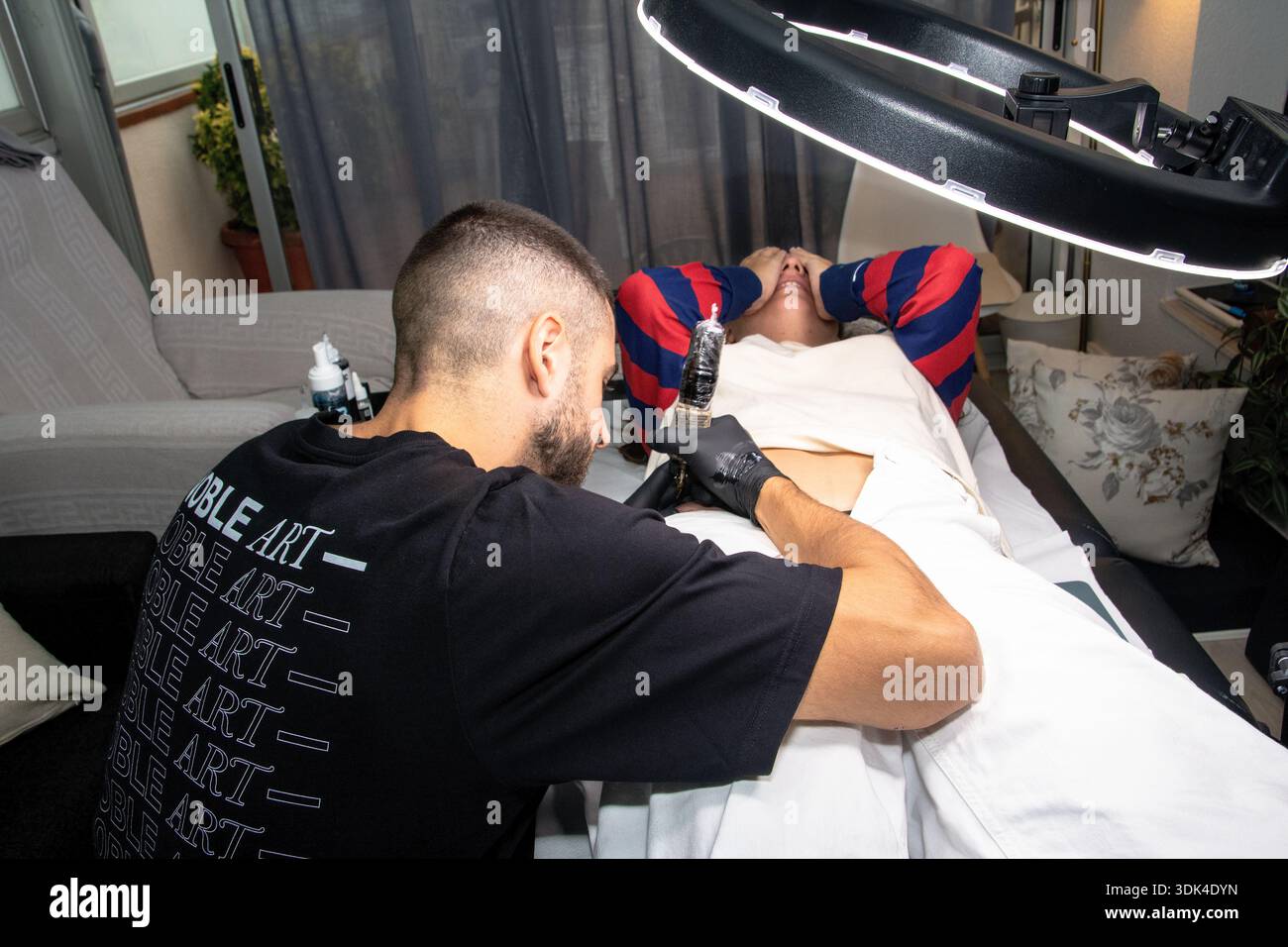 Tattoo artist working on woman's body modification in studio Stock ...