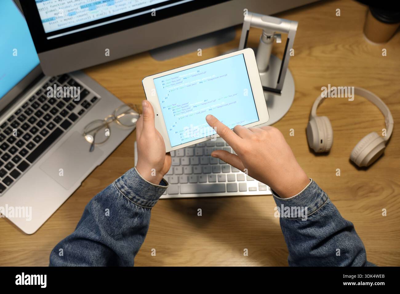 Programmer's hands pointing at modern tablet computer on wooden background Stock Photo