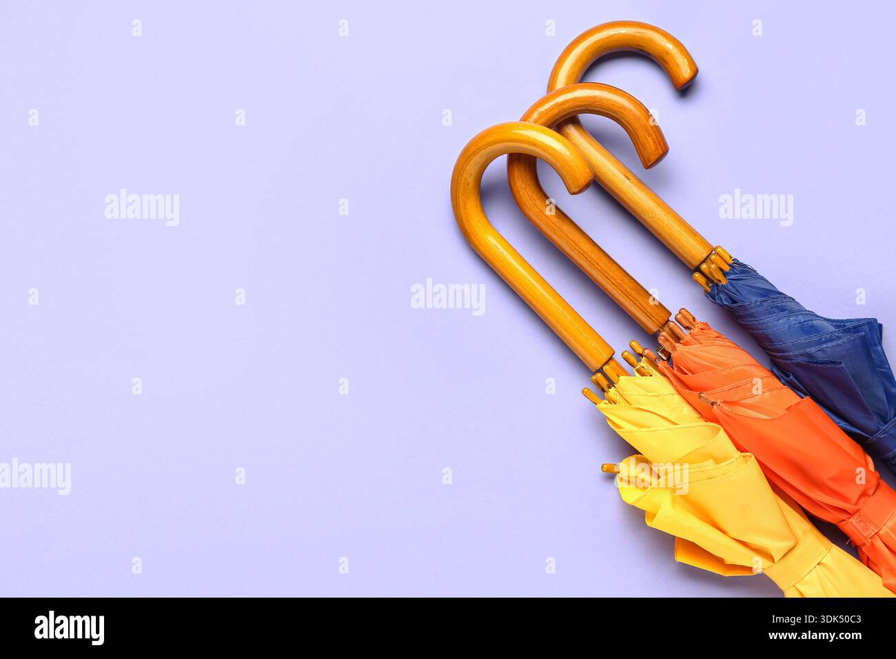Different stylish umbrellas on lilac background Stock Photo