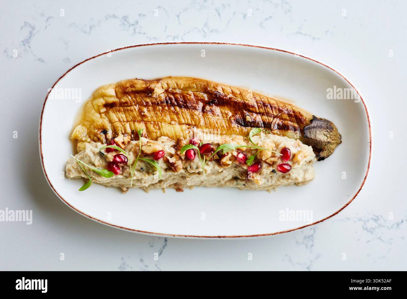 Roasted aubergine and puree with pomegranate seeds and mint Stock Photo