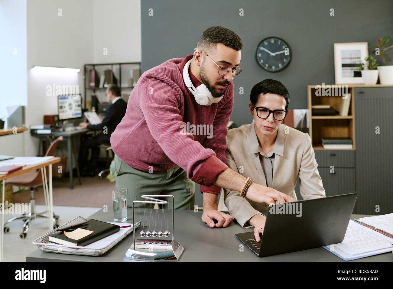 Young Adult Middle Eastern Man Assisting Middle Aged Woman Working Stock Photo