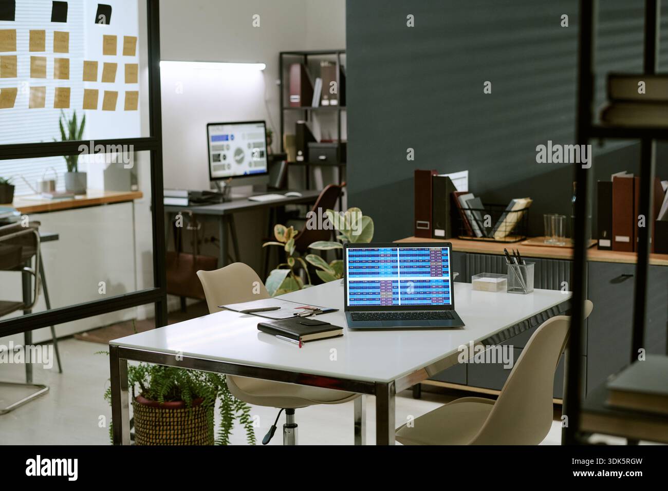 Modern Office Workspace Featuring Laptop Displaying Colorful Data Charts Stock Photo