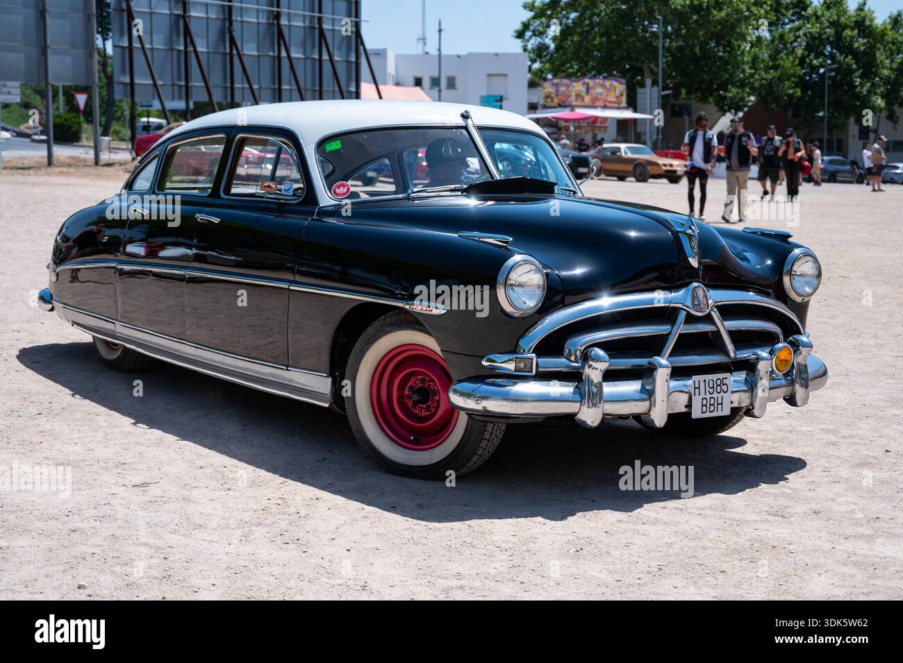 Stunning 1952 Hudson Wasp classic American sedan in black and white with red rims and whitewall tires at a car show. Stock Photo