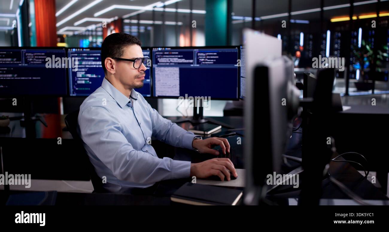 Latin Engineer Develops Code On Desktop Computer In Office Setting. Stock Photo