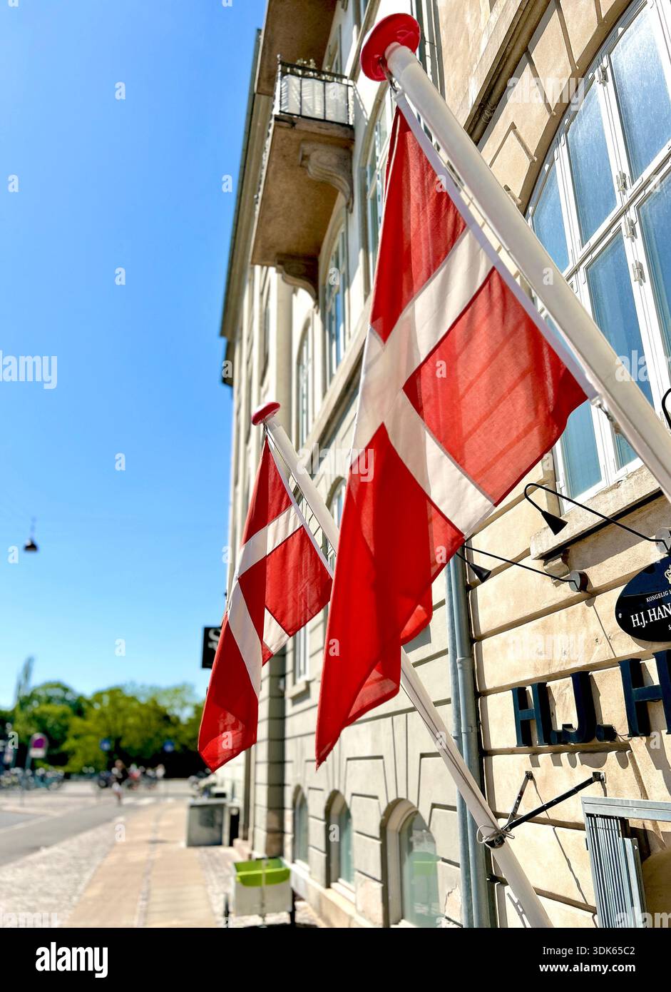 Small Danish wall flag mounted on a building façade in Copenhagen, adding a subtle national detail to the urban streetscape. - Smartphone Captured Stock Image