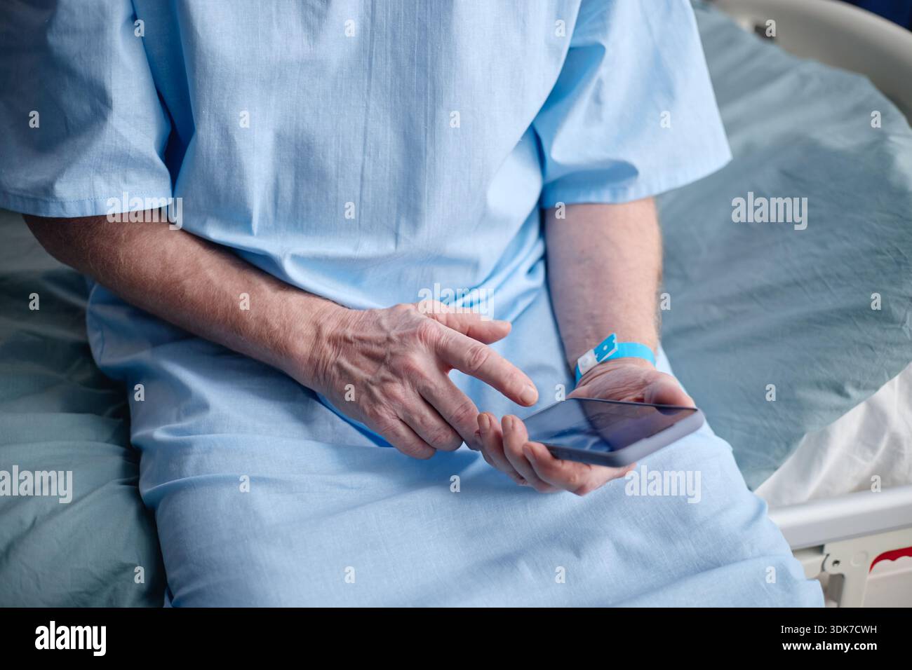 Middle Aged Man Using Digital Tablet While Sitting in Hospital Bed Stock Photo
