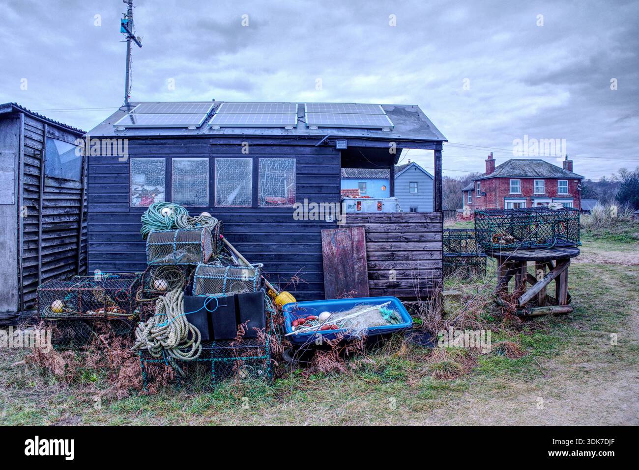 fisherman sheds shacks on sizewell beach Suffolk weatherbeaten weathered battered grey wintery sky ramshackle Stock Photo