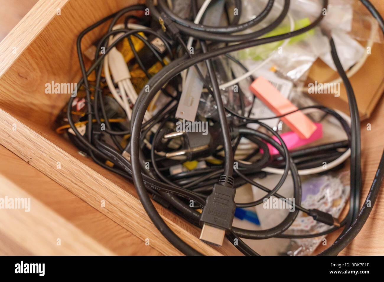 Open drawer with tangled electronic cables, connectors, and miscellaneous items Stock Photo
