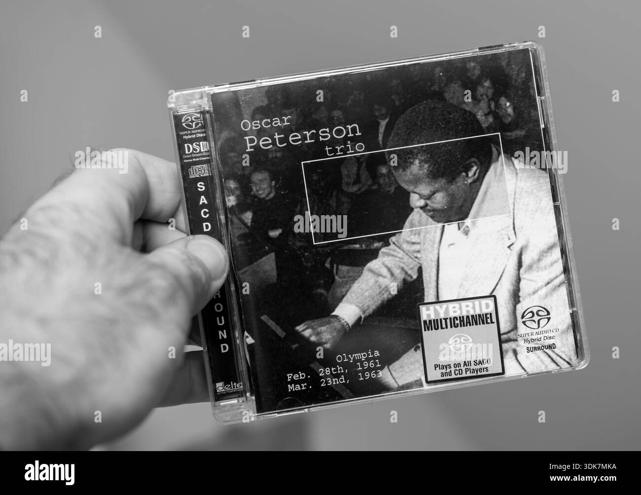 Paris, France - Dec 17, 2025: Man holding Oscar Peterson Trio hybrid multichannel SACD case in monochrome closeup showing jazz pianist album cover and Stock Photo
