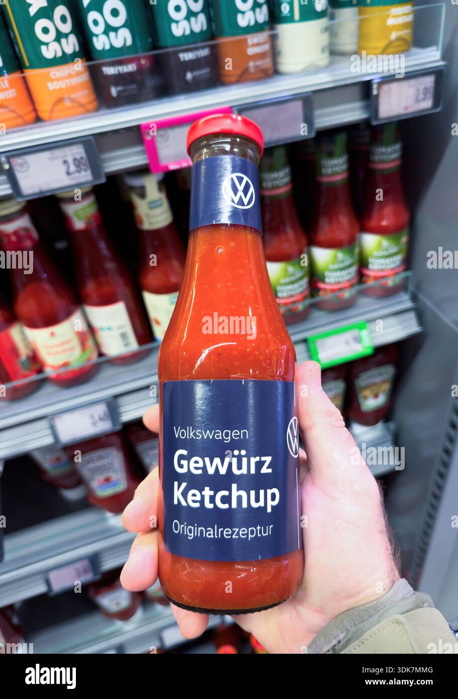 Frankfurt, Germany - Dec 29, 2025: Hand holding Volkswagen Gewurz Ketchup bottle with blue label in supermarket sauce aisle blurred condiment shelves Stock Photo