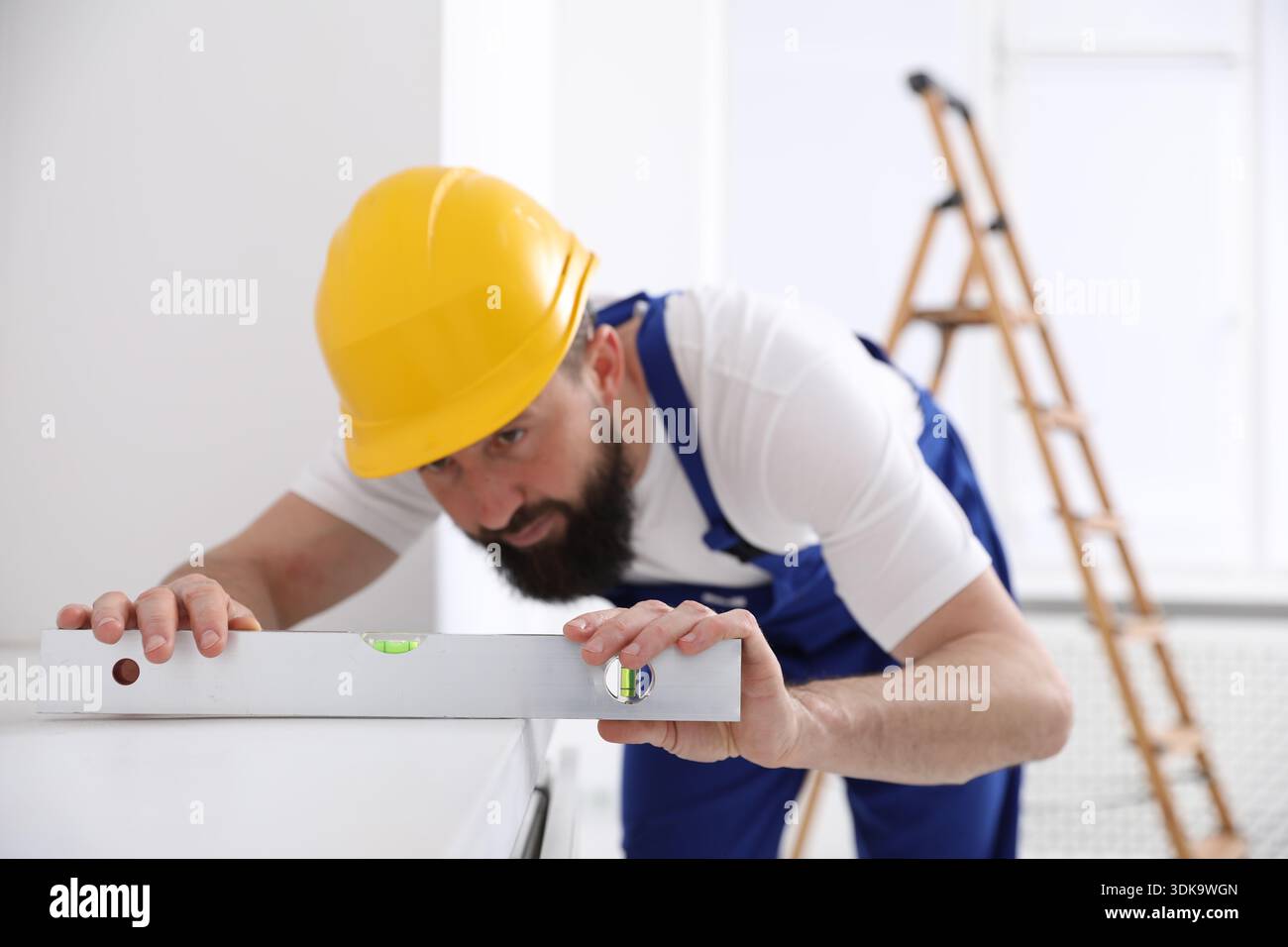 Worker measuring white dresser with building level indoors, selective focus Stock Photo