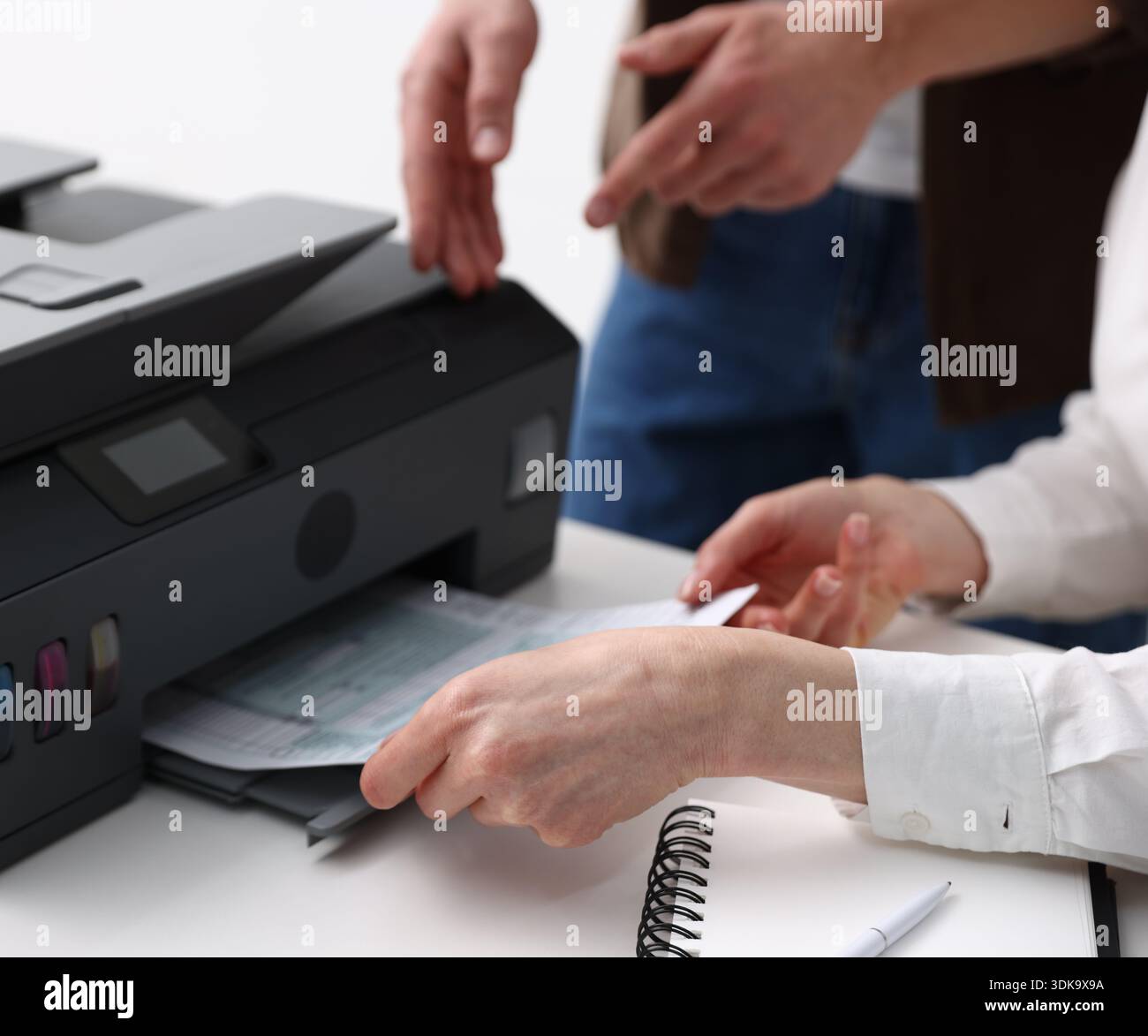 Office workers using printer at white desk indoors, closeup Stock Photo