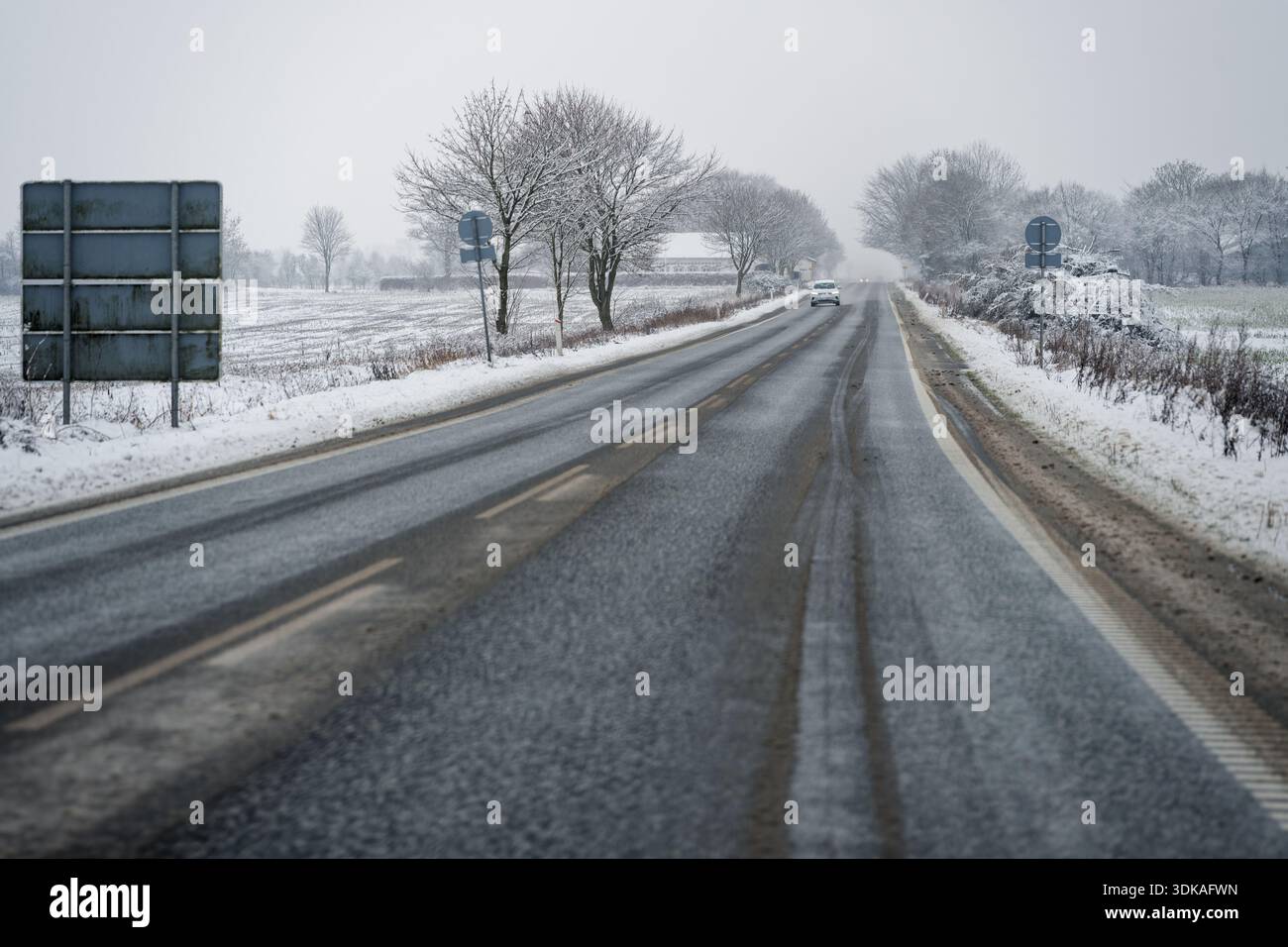 Perspective of a wet asphalt road covered in brown slush and snow ...