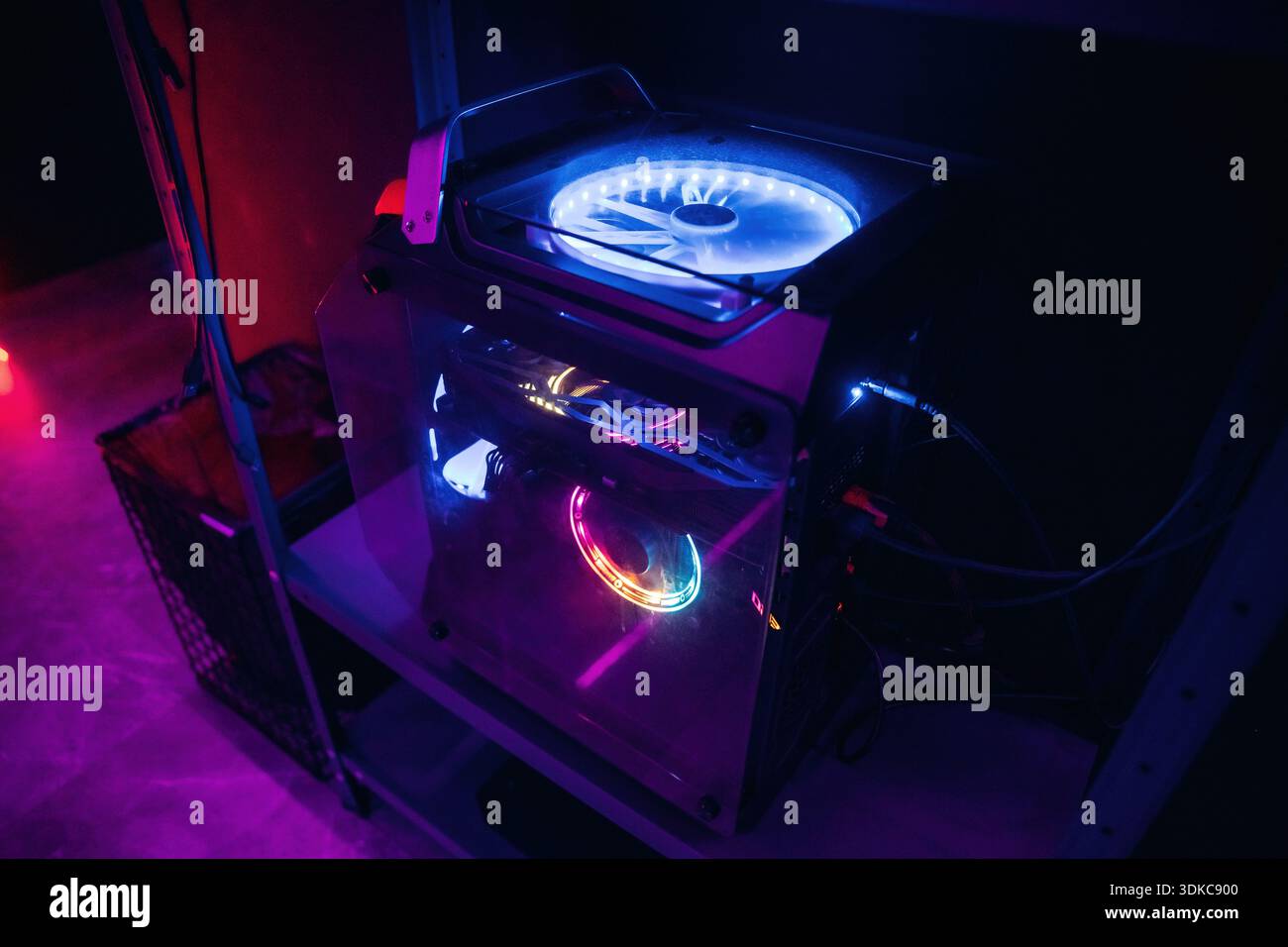 Powerful gaming computer with colorful cooling system in dark room. Stock Photo