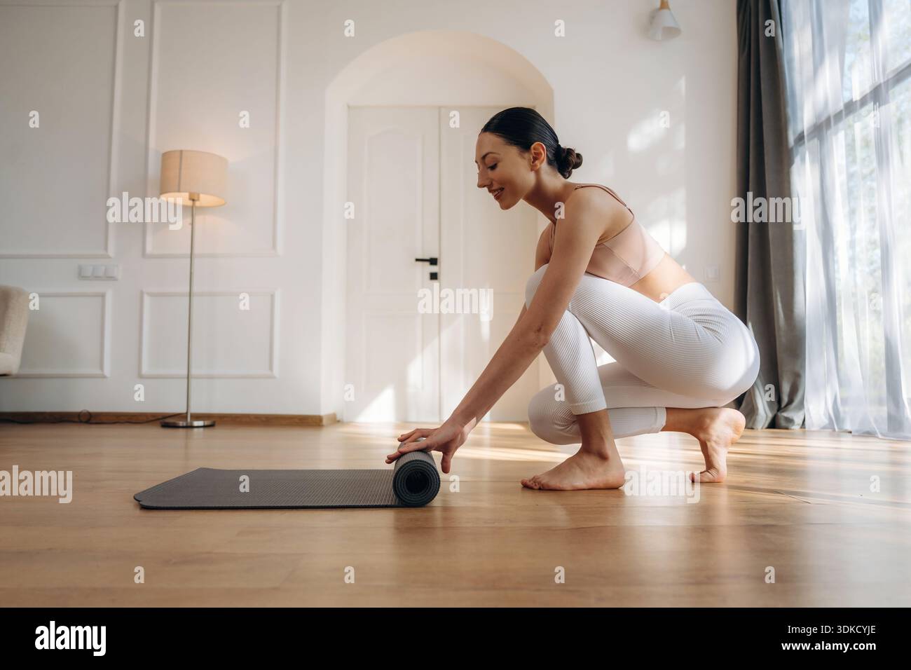 Rolling off the the yoga mat. Young woman in fitness clothes is in the room  Stock Photo - Alamy