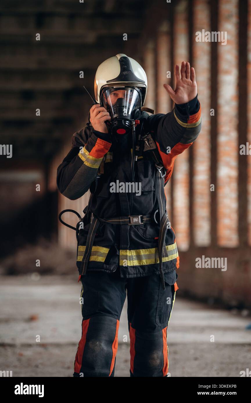 Firefighter Stop Sign Stop hand gesture. Firefighter in professional equipment is indoors in ...