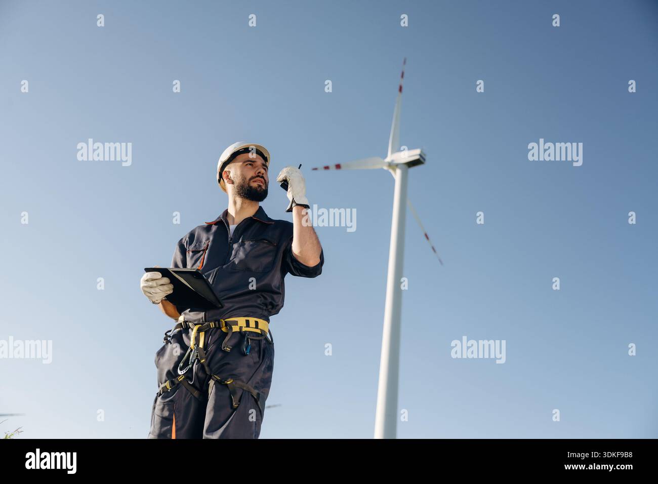 Using walkie talkie. Engineer in field checking on wind turbine production. Stock Photo