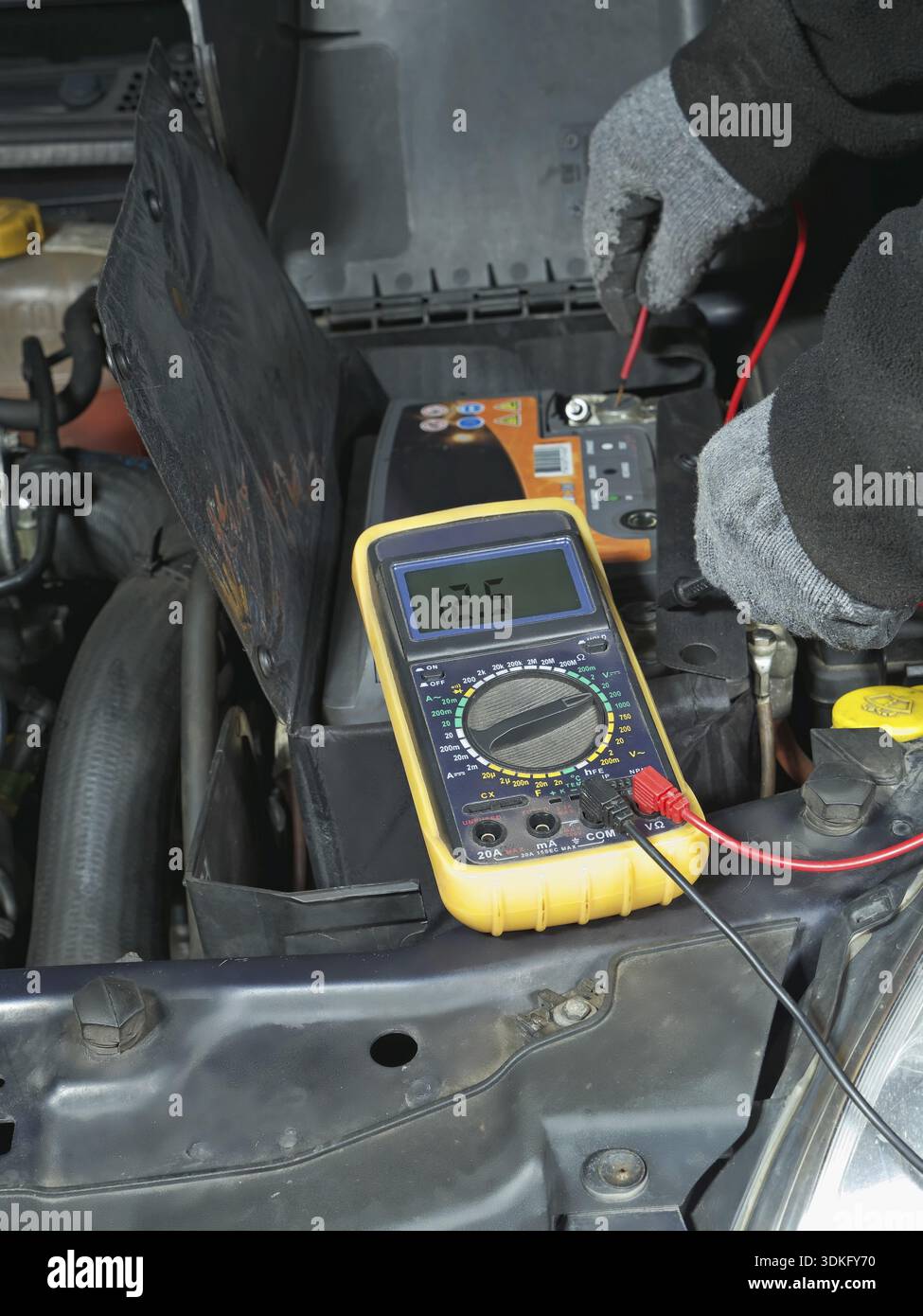 Auto mechanic measuring car battery voltage using multimeter Stock Photo