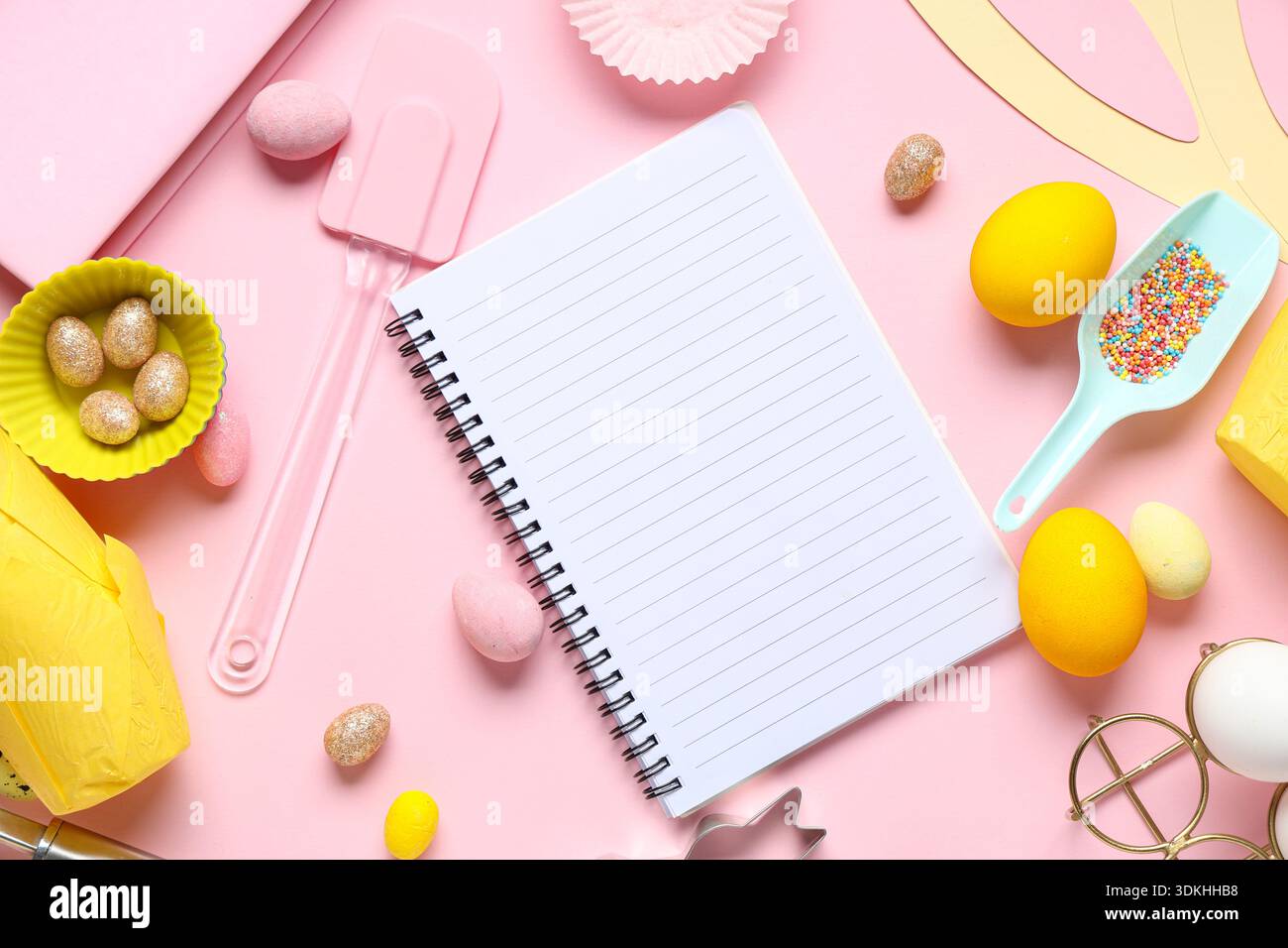 Blank notepad for recipes with Easter eggs and baking tools on pink background Stock Photo