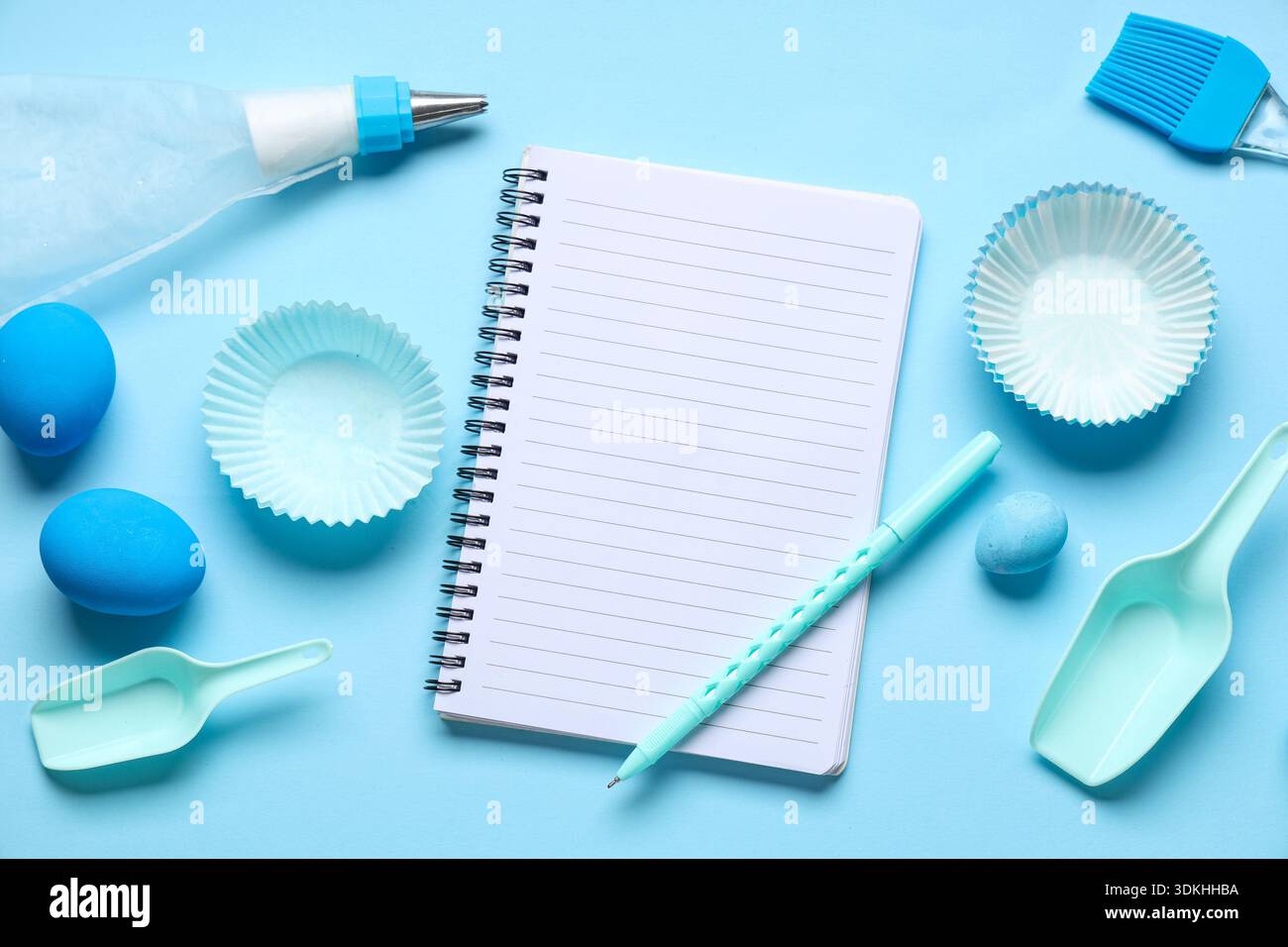 Blank notepad for recipes with pen, baking tools and Easter eggs on blue background Stock Photo