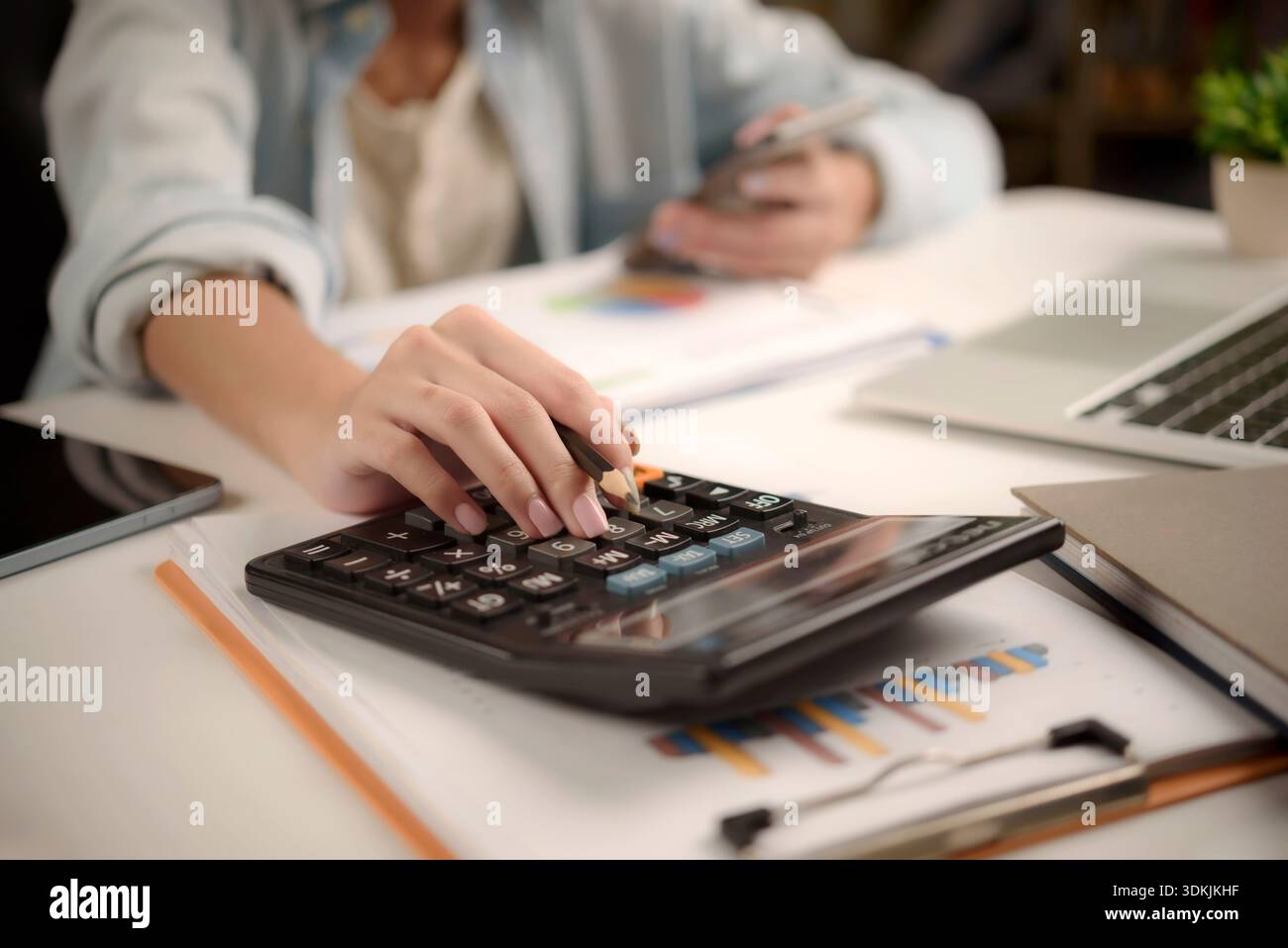 businesswoman using a calculator and analyzing business charts and graphs on desk. financial management, tax planning, and strategic budget analysis. Stock Photo