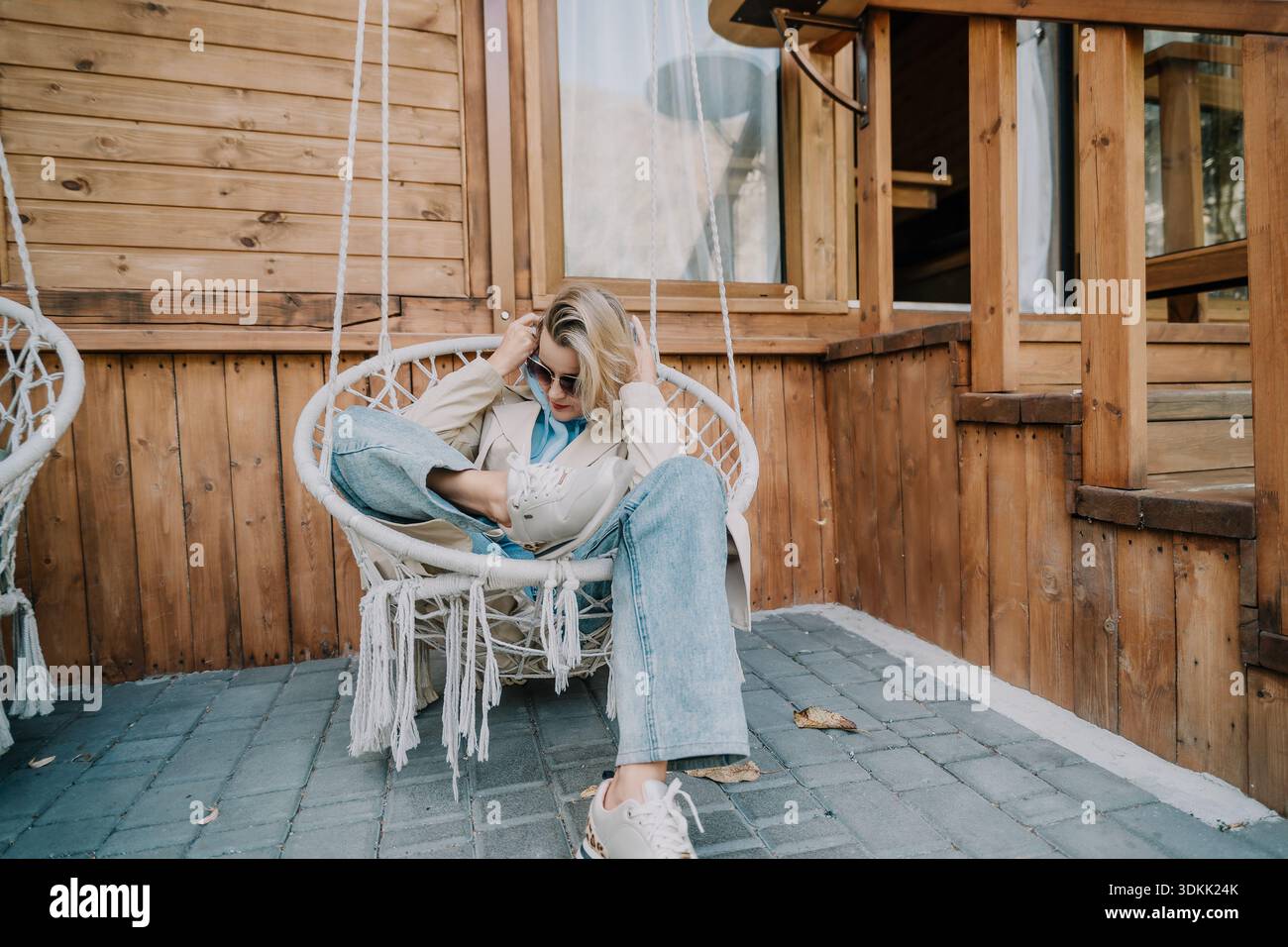 Woman Relaxing in a Hanging Chair on a Patio Stock Photo - Alamy